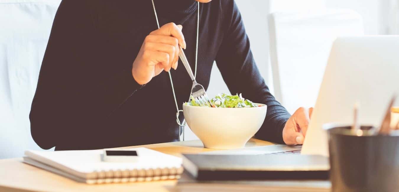 career-driven woman eating a healthy lunch she packed for work