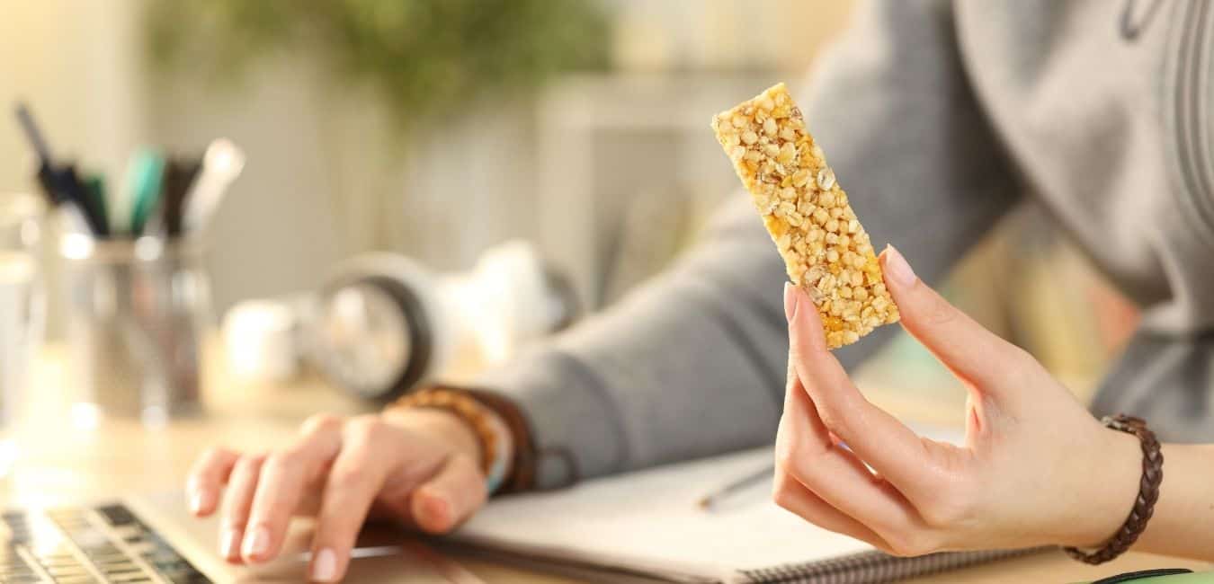 woman eating granola bar while working