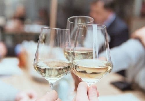 women clinking glasses of white wine for happy hour
